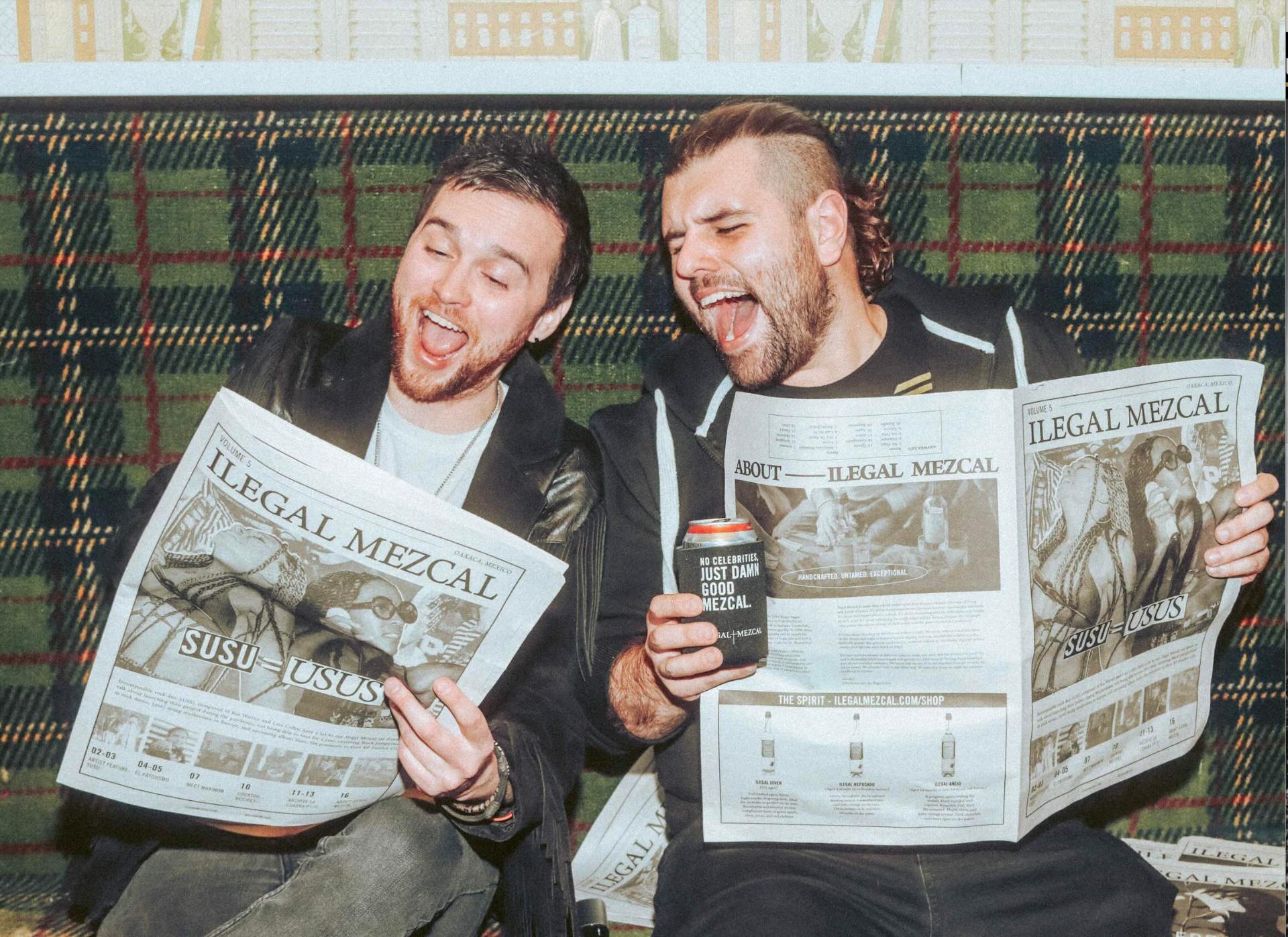 Friends laughing over the Ilegal Mezcal newspaper